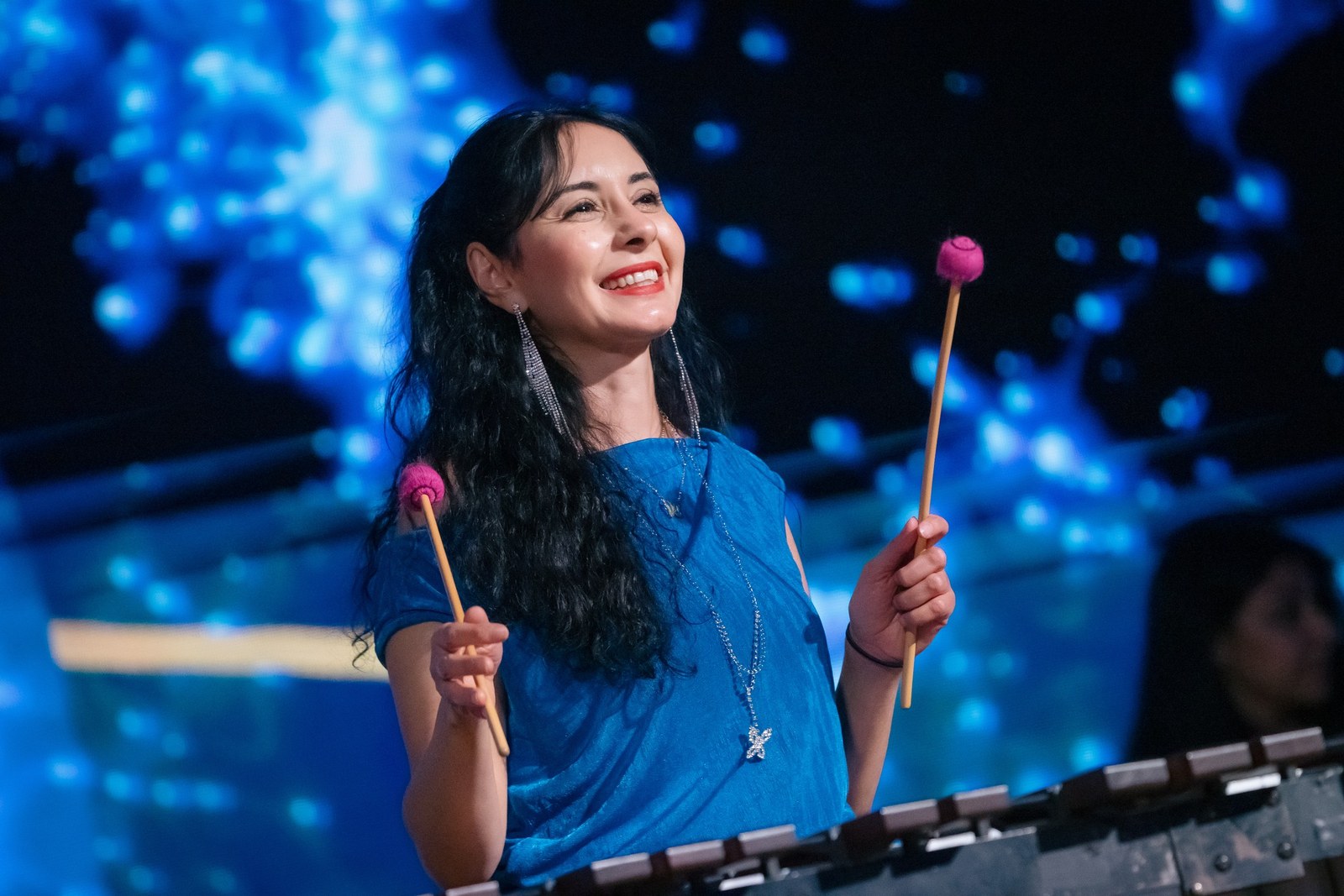 Nesma Abdelaziz smiling with two mallets raised above the marimba